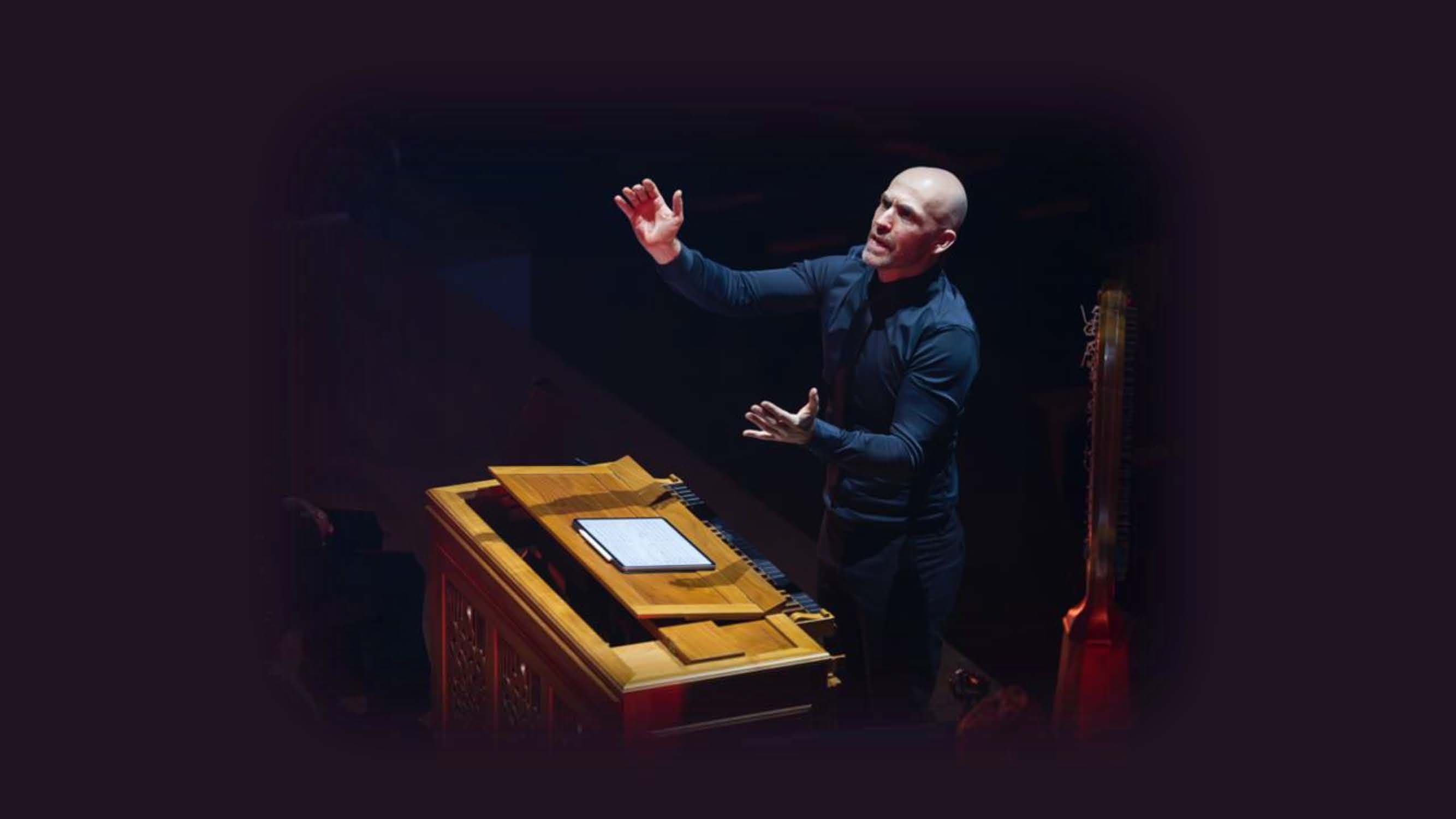 Erin Helyard at the keyboard conducting an orchestra